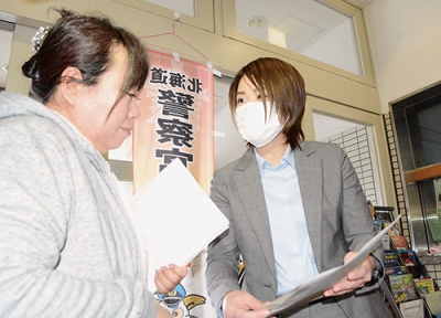 写真：情報提供を呼び掛けるチラシを配布する捜査員