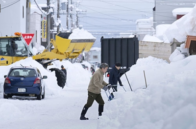 写真：発達した低気圧の影響で大雪となり、雪かきに追われる人たち＝１２日午後１時５７分、札幌市東区