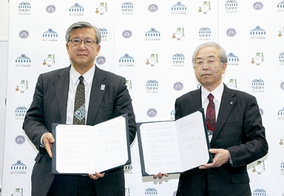 写真：協定書を手にする札幌大学の荒川理事長（右）と堂本理事長