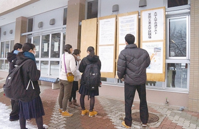 写真：試験場の入り口で掲示板を確認する受験生たち＝１４日午後１時２０分ごろ、室蘭工業大学