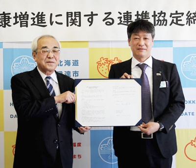 写真：協定書を交わす菊谷市長（左）と七田支社長