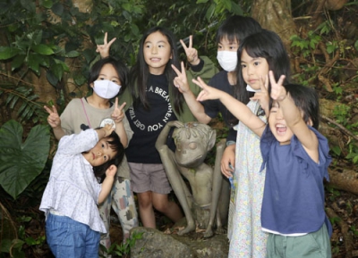 写真：鹿児島県・奄美大島の宇検村で、ケンムン像を巡り答えを見つけ出す謎解きに参加した子どもたち＝１日