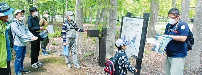 写真：洞爺湖畔で確認できる野鳥などの説明を受ける参加者たち