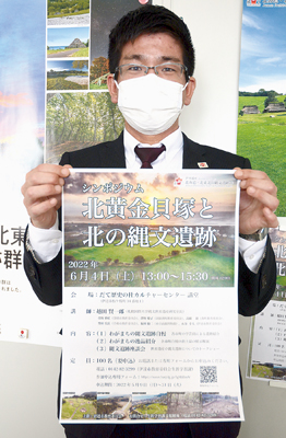 写真：ポスターを手にシンポジウムへの参加を呼び掛ける永谷学芸員