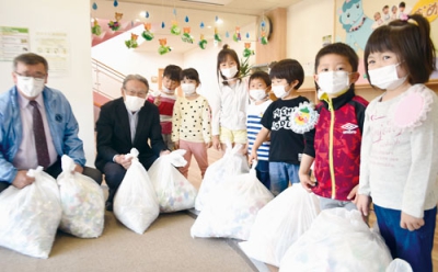 写真：ペットボトルキャップなどを寄贈する子どもたち