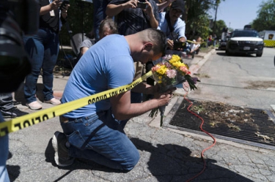 写真：２５日、銃乱射事件が起きた小学校で、犠牲者を悼んで祈る男性＝米テキサス州ユバルディ（ＡＰ＝共同）