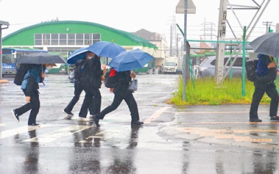 写真：雨が降る中、水たまりを避けて歩く下校中の生徒ら＝２７日午後３時ごろ、室蘭市東町の道南バス東町ターミナル