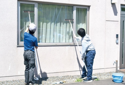 写真：丁寧に窓を拭き上げる生徒（ケアハウスオパール八丁平）