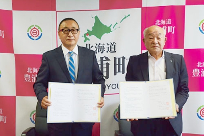 写真：空き家対策での連携に向けて協定書に署名した村井町長（右）と須藤代表理事