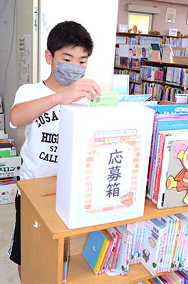 写真：図書館を表す漢字一字を応募箱に投函する小学生