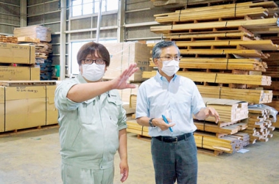 写真：材料置き場の保管状況について山田工場長（左）から説明を受ける齋藤さん
