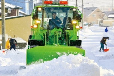 写真：住宅街を除雪車が通る中、雪かきをする市民ら＝８日午前１０時ごろ、登別市富岸町