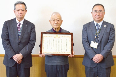 写真：表彰状を持つ「ピノキオ読み聞かせの会」の松本代表（中央）