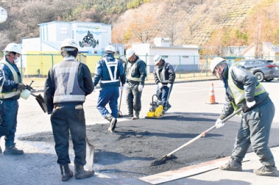 写真：駐車場に空いた穴をアスファルト化合物でならす富士建設の社員たち