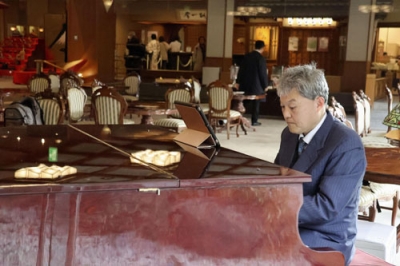 写真：新潟市の岩室温泉にある旅館「穂々」でピアノを演奏する坪田圭司さん＝３月