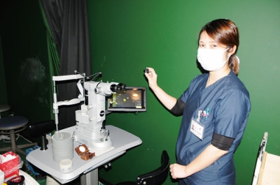 写真：眼科用パルスレーザー手術装置について説明する根岸医師