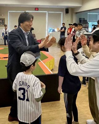 写真：ユニバーサル野球のイベントで参加者とハイタッチする松井秀喜さん（左）＝２１日、ニューヨーク（共同）