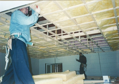写真：断熱性能向上のため、天井裏にグラスウールを充填する様子