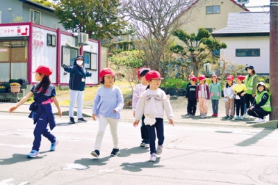 写真：講師らに見守られながら横断歩道を渡る児童たち