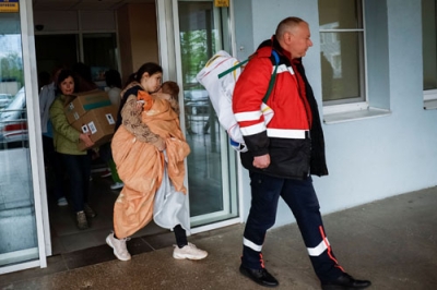 写真：２６日、ウクライナ・キーウの病院から避難する子どもを抱えた女性（右から２人目）（ロイター＝共同）