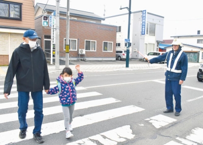 写真：署員が見守る中、幌別小近くの横断歩道を渡る児童ら