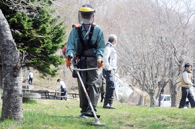写真：草刈りやごみ拾いに取り組む参加者たち