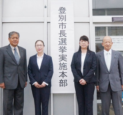 写真：市役所第２庁舎入り口に看板を設置した和田本部長（左端）ら委員