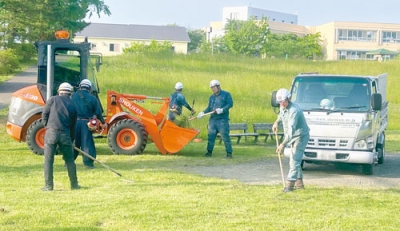 写真：公園敷地内の草刈り奉仕に汗を流す松建の社員（提供写真）