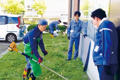 写真：社屋敷地内で草刈りに励む社員たち