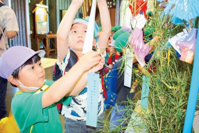写真：願い事を書いた短冊を七夕飾りに取り付ける園児たち