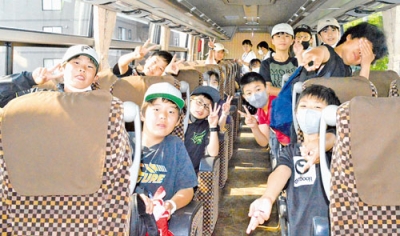 写真：修学旅行に向かうバスに乗り込み喜ぶ６年生