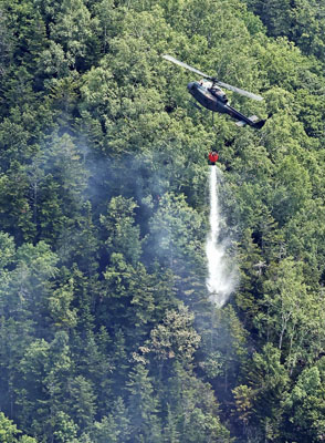 写真：幌加山の火災現場付近で、上空から放水する陸上自衛隊ヘリ＝４日午前１０時５４分（共同通信社ヘリから）