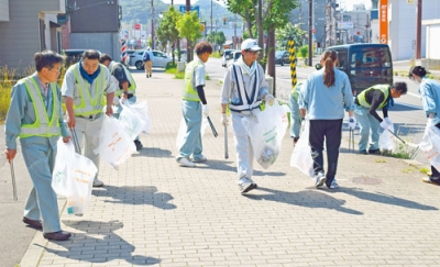 写真：歩道のごみを拾い集める富士建設の社員