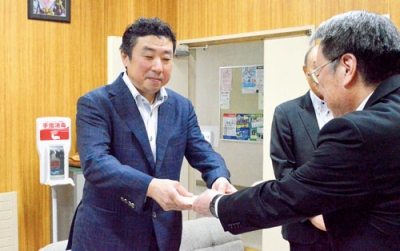 写真：ソフトクリーム無料券を安宅教育長に渡す三浦代表取締役（左）