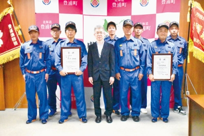 写真：沼舘副町長（中央）にポンプ車操法優勝など結果を報告した豊浦消防団員