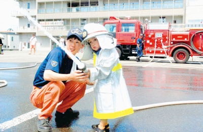 写真：消防士姿で放水体験する参加者