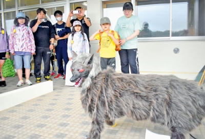 写真：ウルと名付けられたオオカミ型ロボット「モンスターウルフ」を見学する子どもたち
