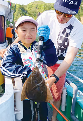 写真：「重たーい」。釣ったカレイに笑みを見せる男の子（提供写真）