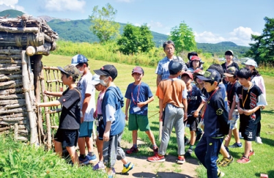 写真：入江貝塚の竪穴住居を見学する苫小牧の小学生たち