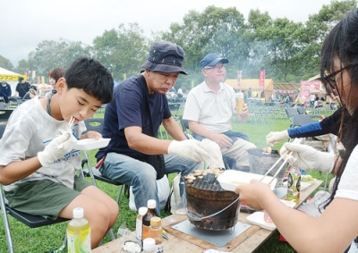 写真：コンロを囲んでバーベキューを楽しむ家族連れ