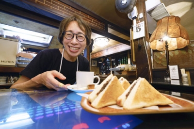 写真：多くの客が注文するあんトーストを前に笑顔を見せる、喫茶店「珈琲処カラス」のオーナー西脇美穂さん＝５日、名古屋市