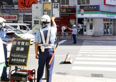 写真：持ち運び可能な発電機（左下）から給電し、信号を作動させる警察官＝６日午前、札幌市