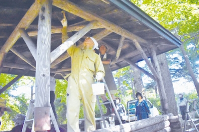 写真：はけで公園内の東屋に防腐剤を塗る会員ら