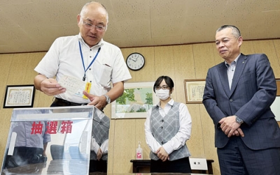 写真：抽選箱から応募用紙を引く室蘭運輸支局の相田支局長（左）