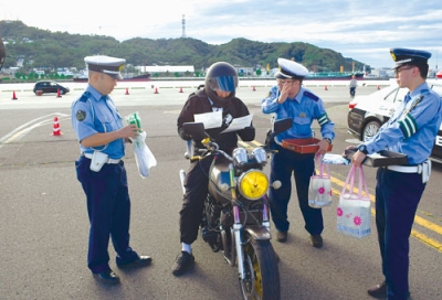 写真：ライダーに安全運転を呼びかける室蘭署員