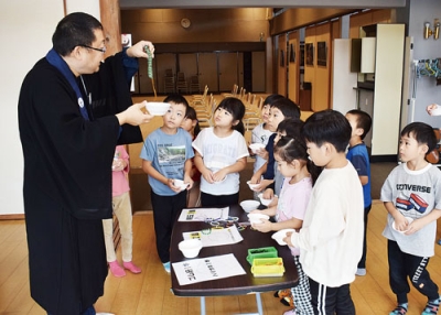 写真：高倉住職から念球の作り方を教わる白鳥保育所の園児たち