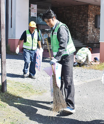 写真：ホテルローヤル周辺で刈り取った草をほうきで集める伊達ＬＣ会員