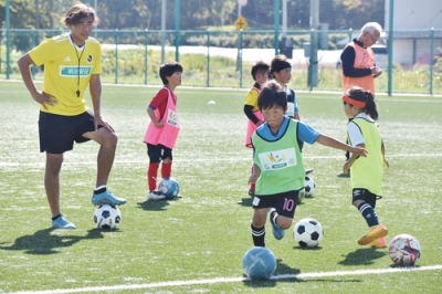 写真：サッカー元日本代表の本山さん（左）から指導を受ける子どもたち