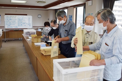 写真：書類を丁寧に封筒に納める奉仕員たち