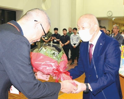 写真：職員から花束を受け取る村井町長（右）